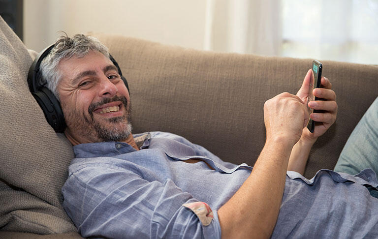 man smile beard couch earphone