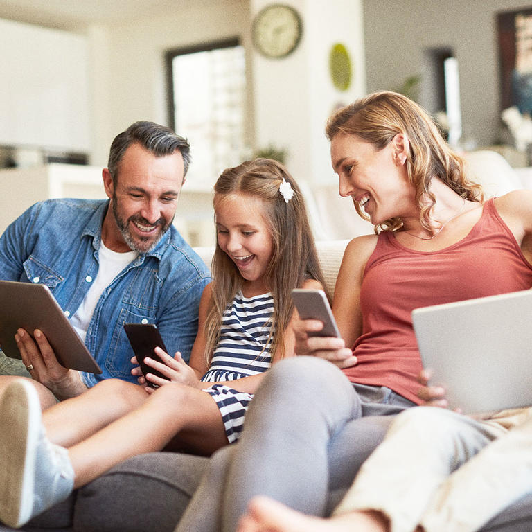 Famille sourire téléphone tablette sofa