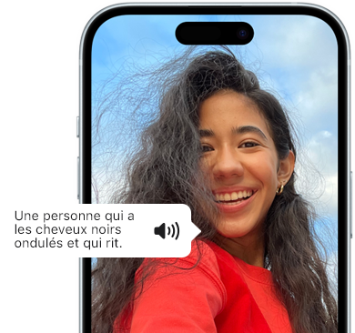 Un iPhone 15 affichant la fonctionnalité VoiceOver en train de lire les renseignements d’une image : Une personne avec les cheveux noirs ondulés en train de rire.